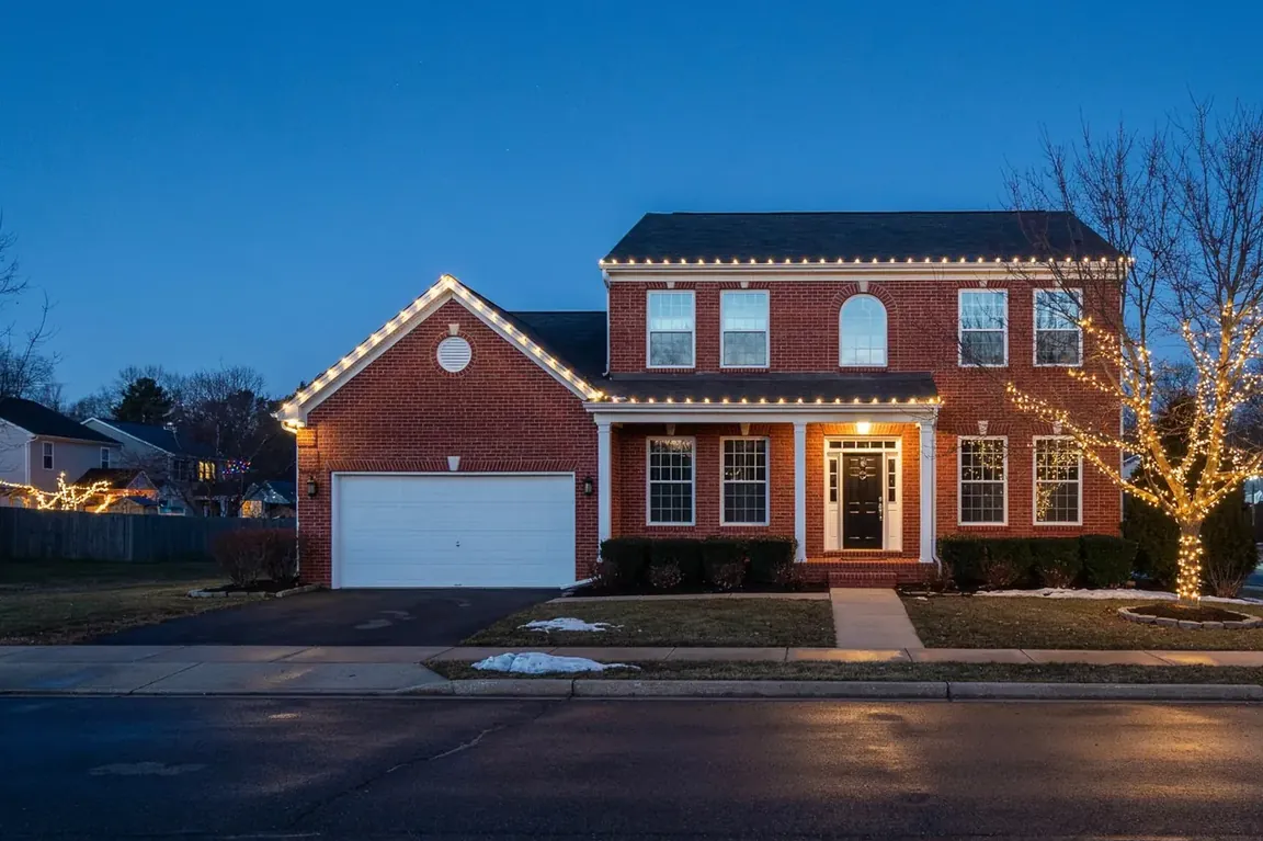 Brick colonial with warm white C9 lights on the roofline and garage gable