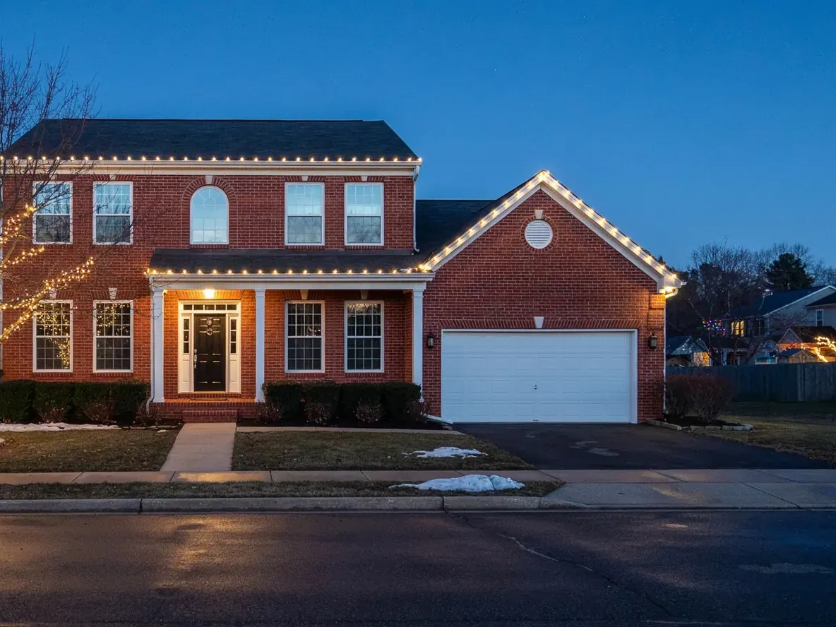 Two-story colonial with warm white C9 lights on the roofline, porch, and garage gable